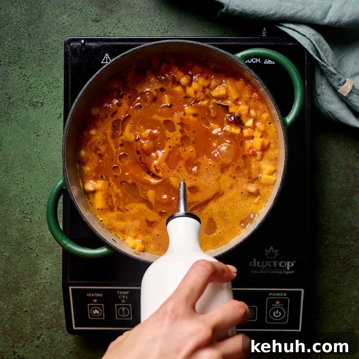 Person stirring vegan tagine in a dutch oven.