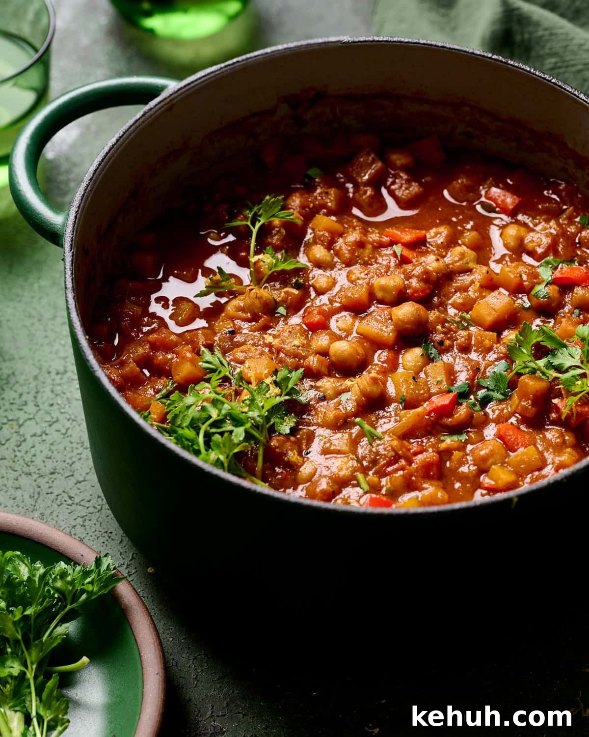 Side view of dutch oven filled with tagine on a green table.