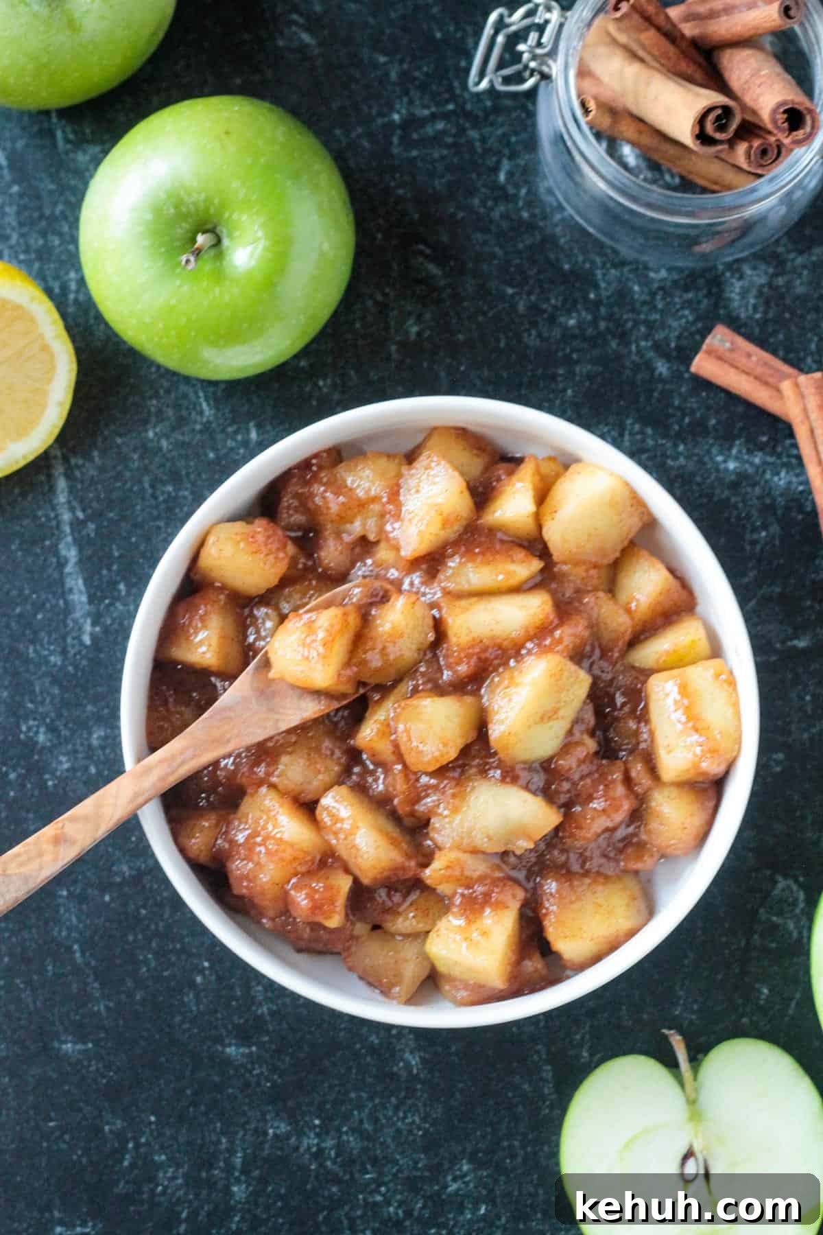 Stovetop Cinnamon Apples Recipe — Quick Comfort Dessert 2 Small wooden spoon scooping up stovetop cinnamon apples from a bowl.