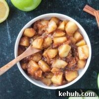 Stovetop Cinnamon Apples Recipe — Quick Comfort Dessert 12 Small wooden spoon scooping up stovetop cinnamon apples from a bowl.