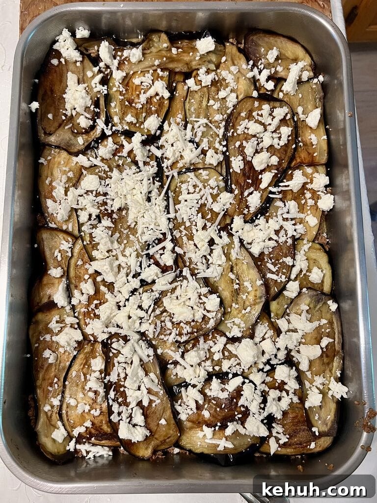 Sprinkling feta on top of eggplant.
