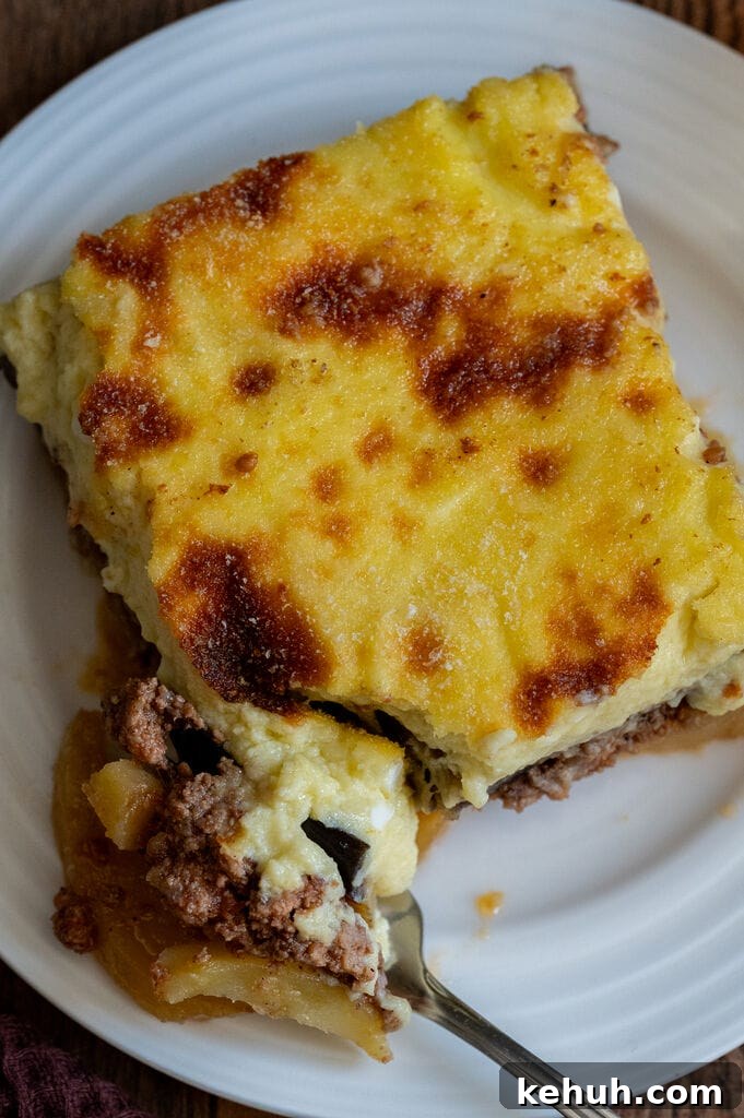 A piece of moussaka on a white plate.