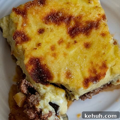 A piece of moussaka on a white plate.
