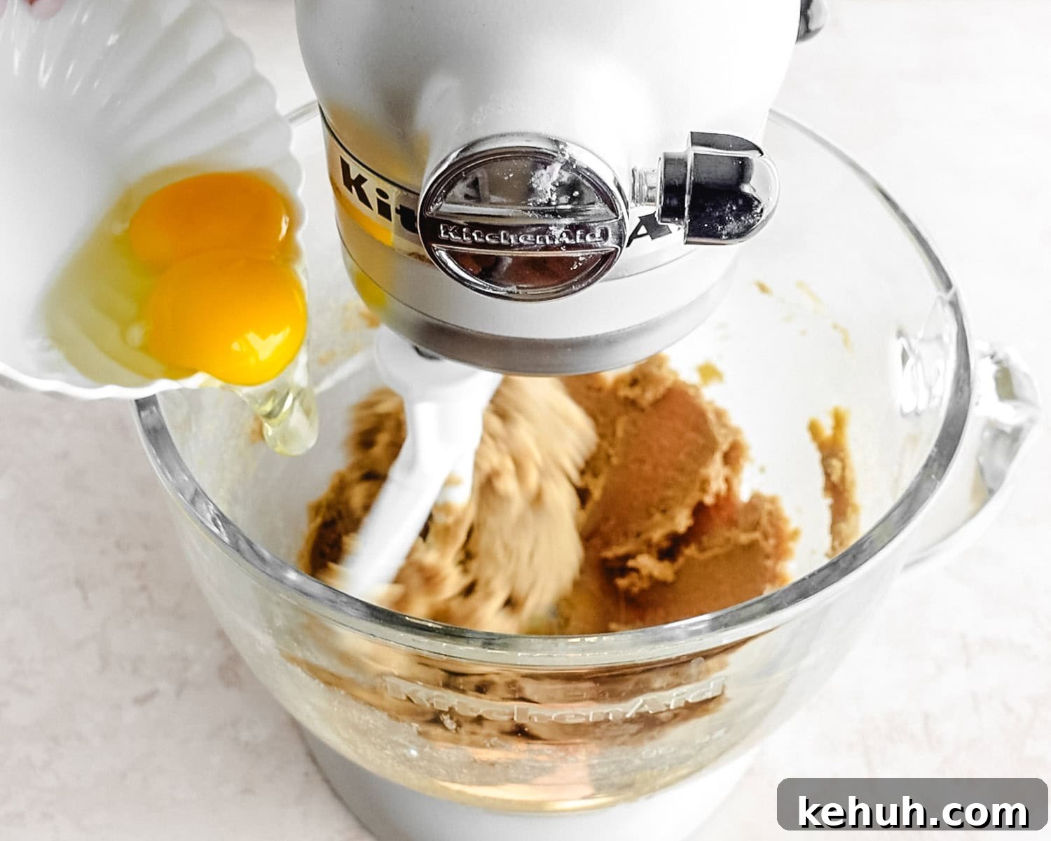Add the egg and egg yolk to the mixture in the mixing bowl.