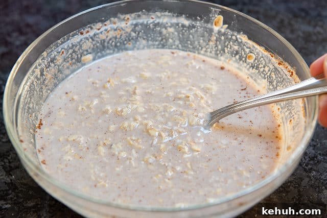 Old Fashioned Oats Soaked in Almond Milk, Sweetener, and Spices in Mixing Bowl