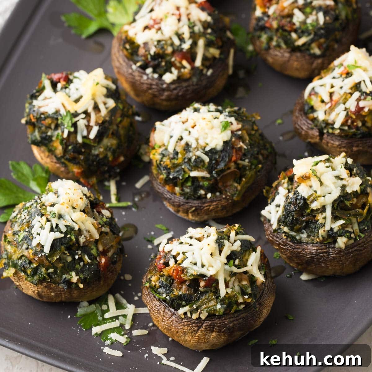 Parmesan Spinach-Stuffed Mushrooms: Savory Appetizer Recipe 15 Spinach stuffed mushrooms on a gray serving plate with melted parmesan and parsley.
