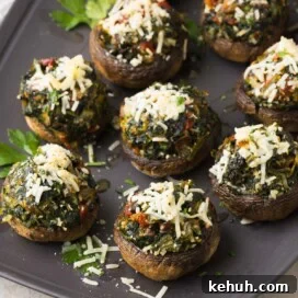 Parmesan Spinach-Stuffed Mushrooms: Savory Appetizer Recipe 20 Spinach stuffed mushrooms on a gray serving plate with melted parmesan on top, with parsley.