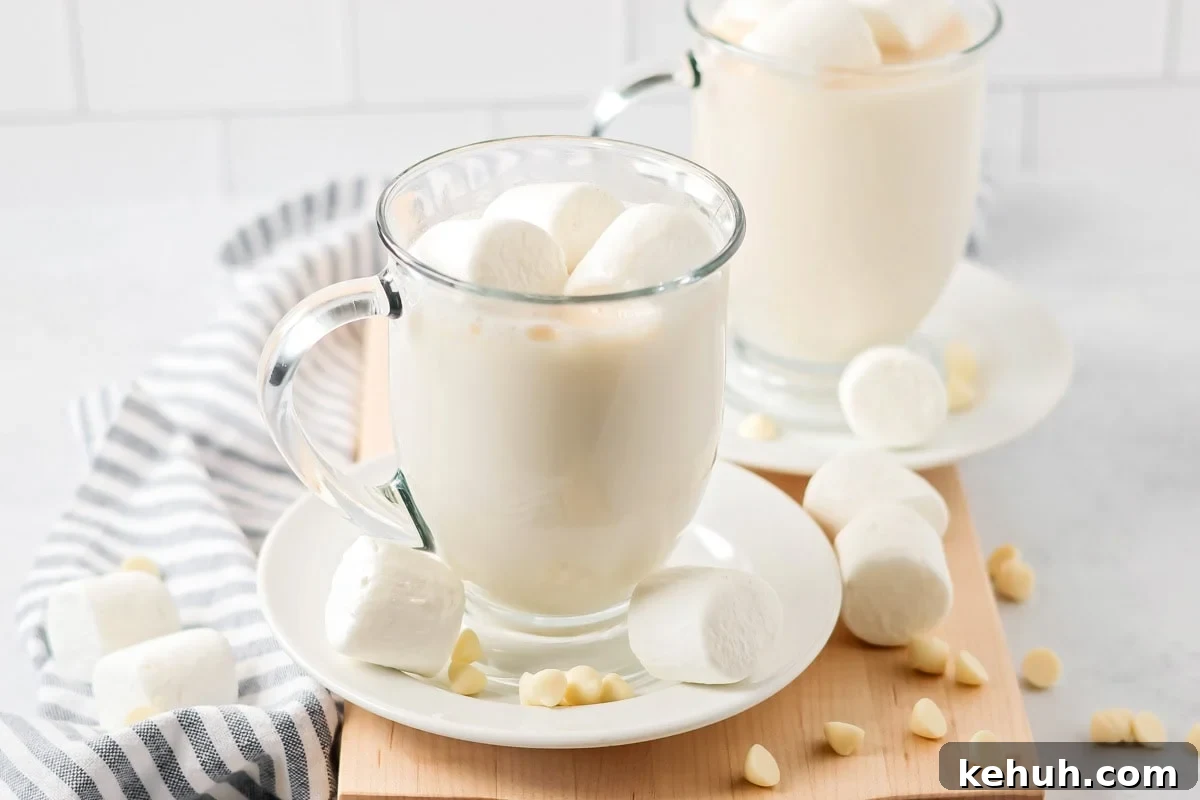 White chocolate hot cocoa in glass mug with marshmallows.