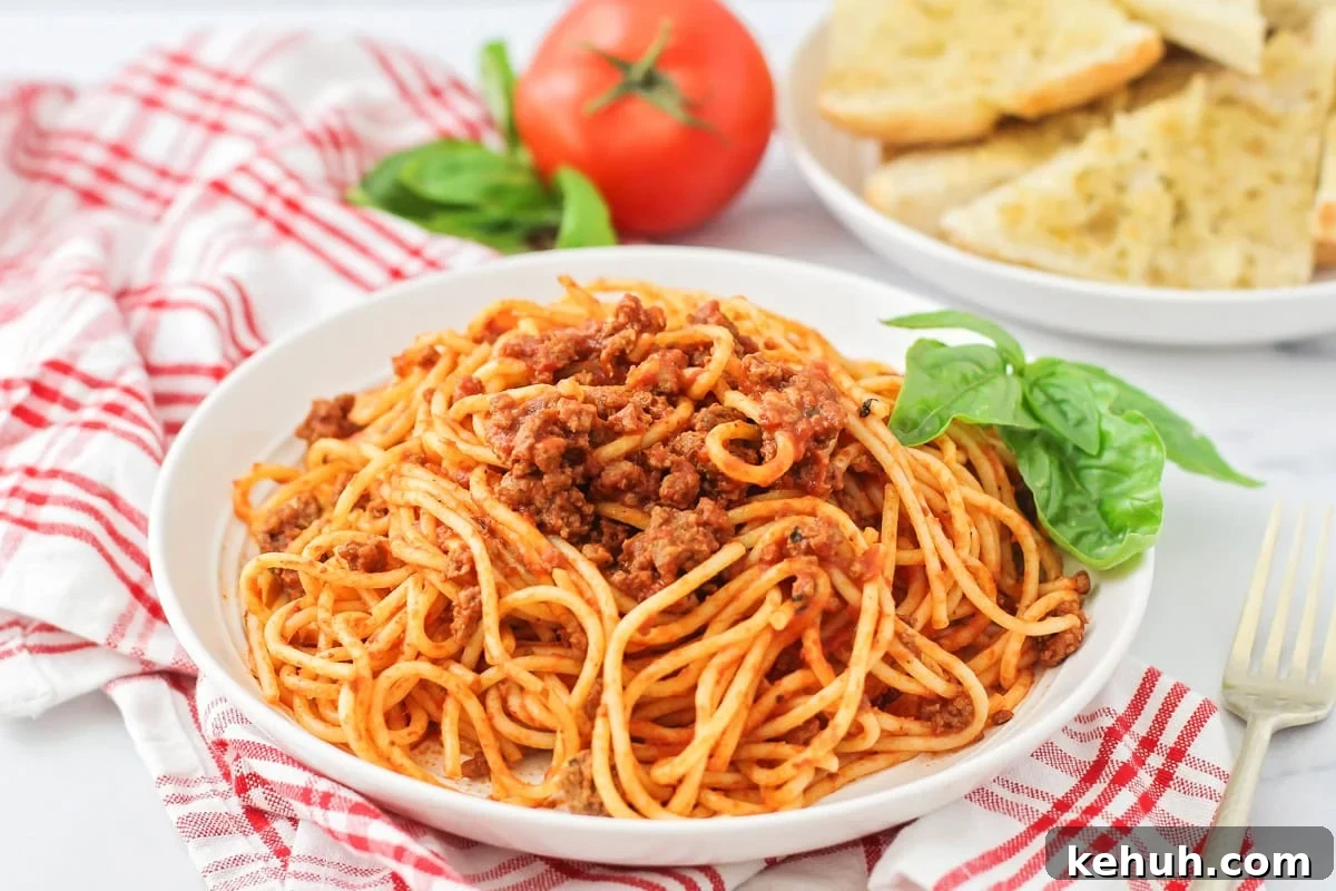 Easy spaghetti recipe dished on white plate with basil on the side.