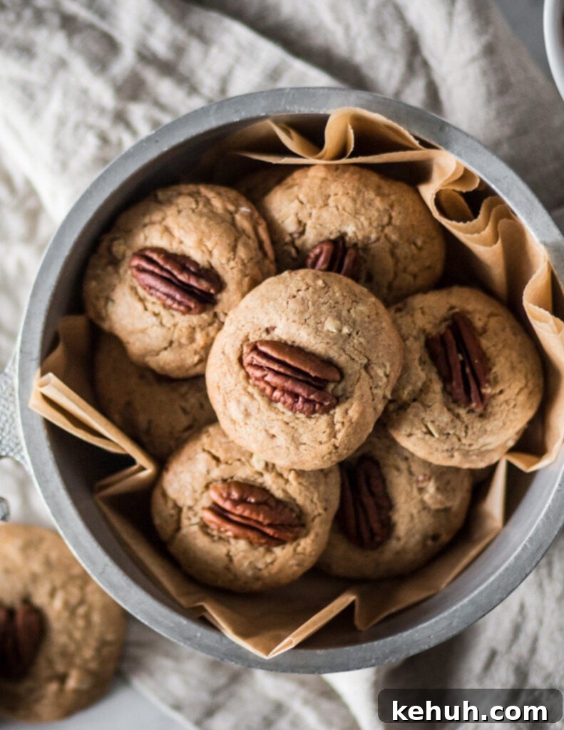 Gluten-Free Butter Pecan Cookie Recipe: Crisp, Nutty Cookies 3 a silver bowl of gluten free butter pecan cookies next to a bowl of pecans on a marble surface