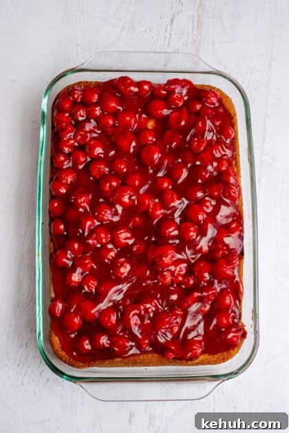 Smoothing out the layer of cherry pie filling on the lemon cherry cheesecake