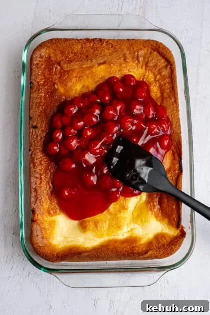 Adding cherry pie filling to the baked lemon cherry cheesecake base