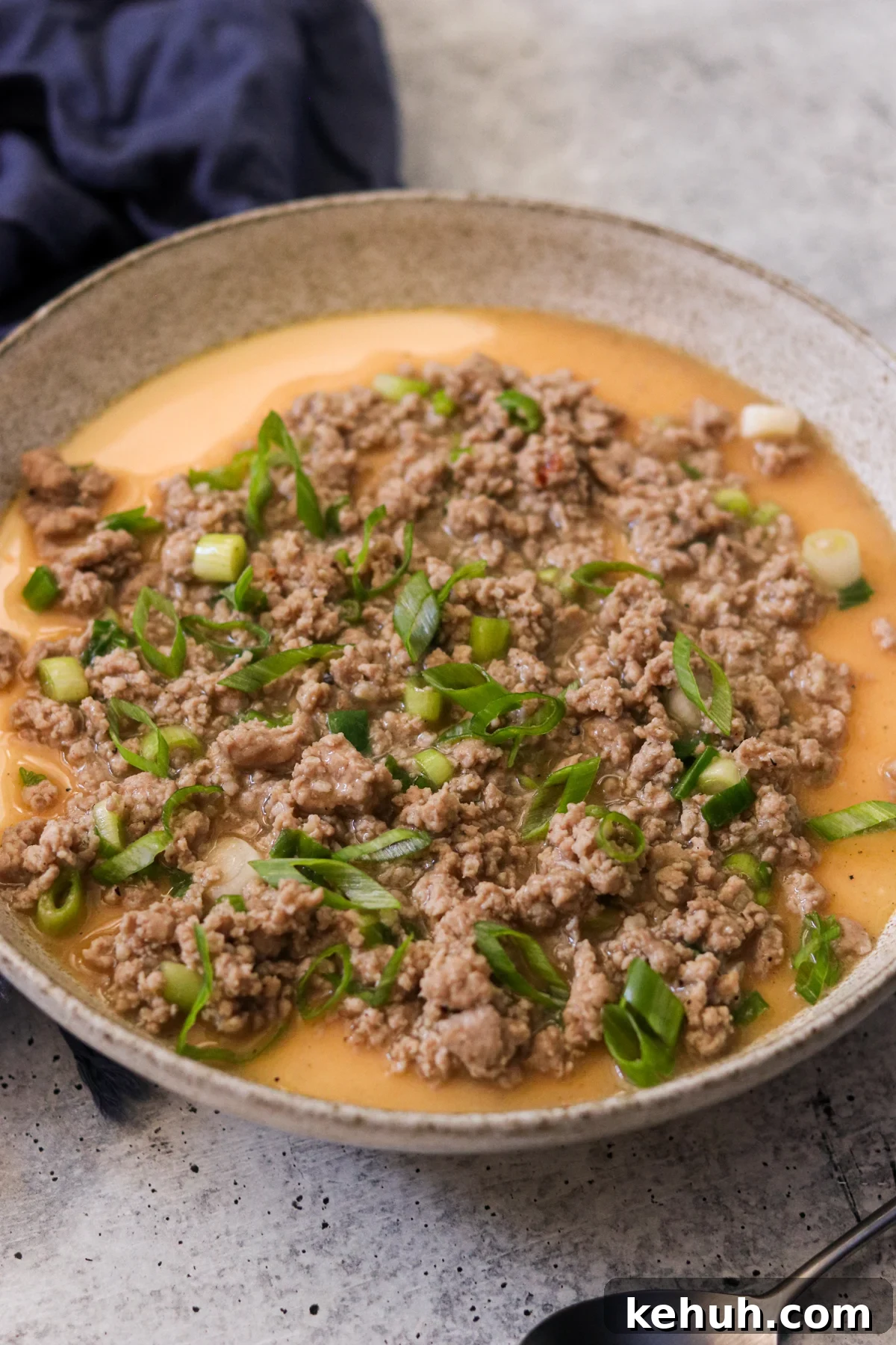 a bowl of Chinese steamed egg topped with ground pork and chopped green onions