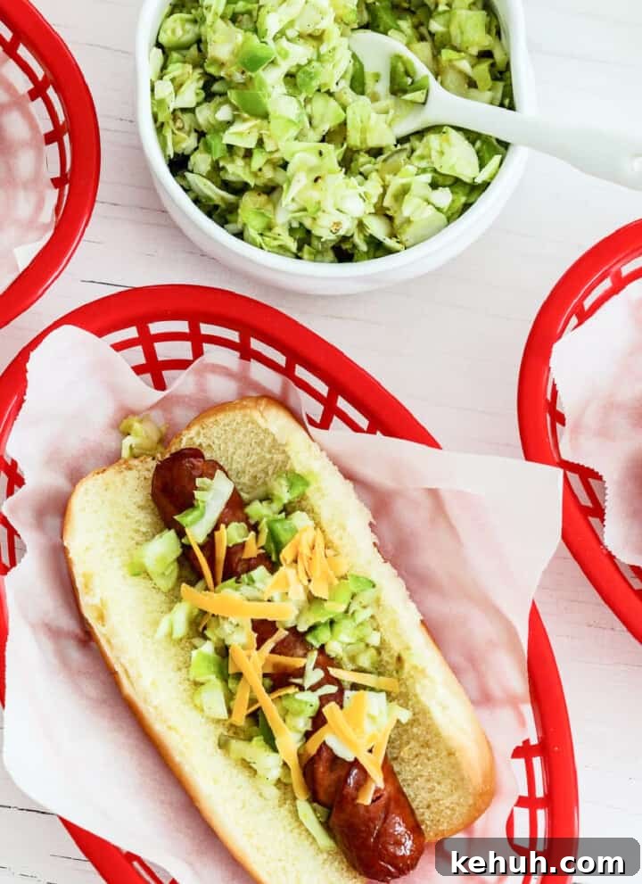 A red plastic food basket lined with paper holding a loaded grilled hot dog.