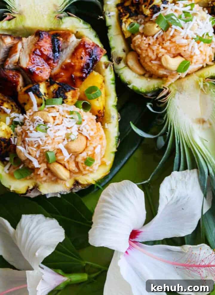 Two pineapple halves carved out filled with coconut rice, grilled pineapple and huli huli chicken.