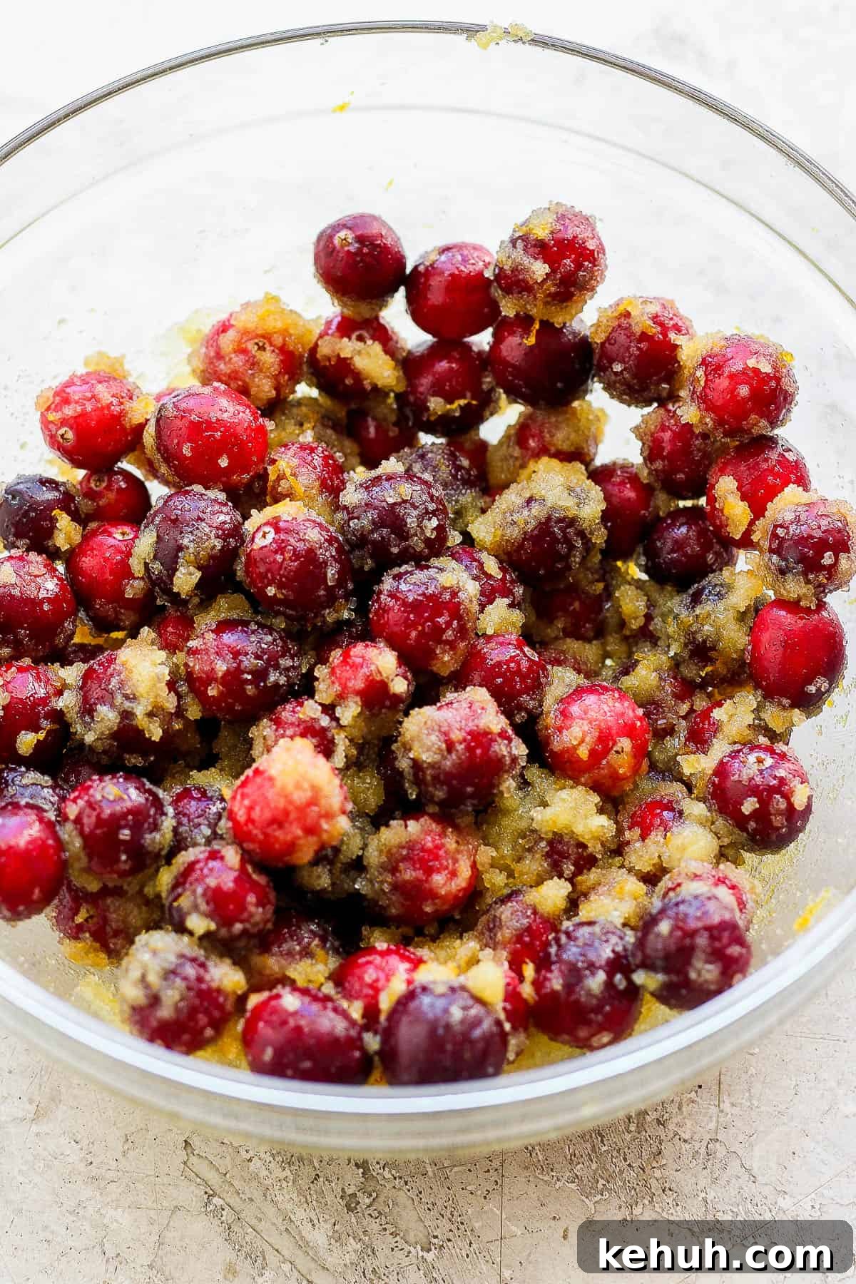 A medium bowl with cranberries coated in the cornstarch, cane sugar, orange zest, orange juice and vanilla extract mixture. 