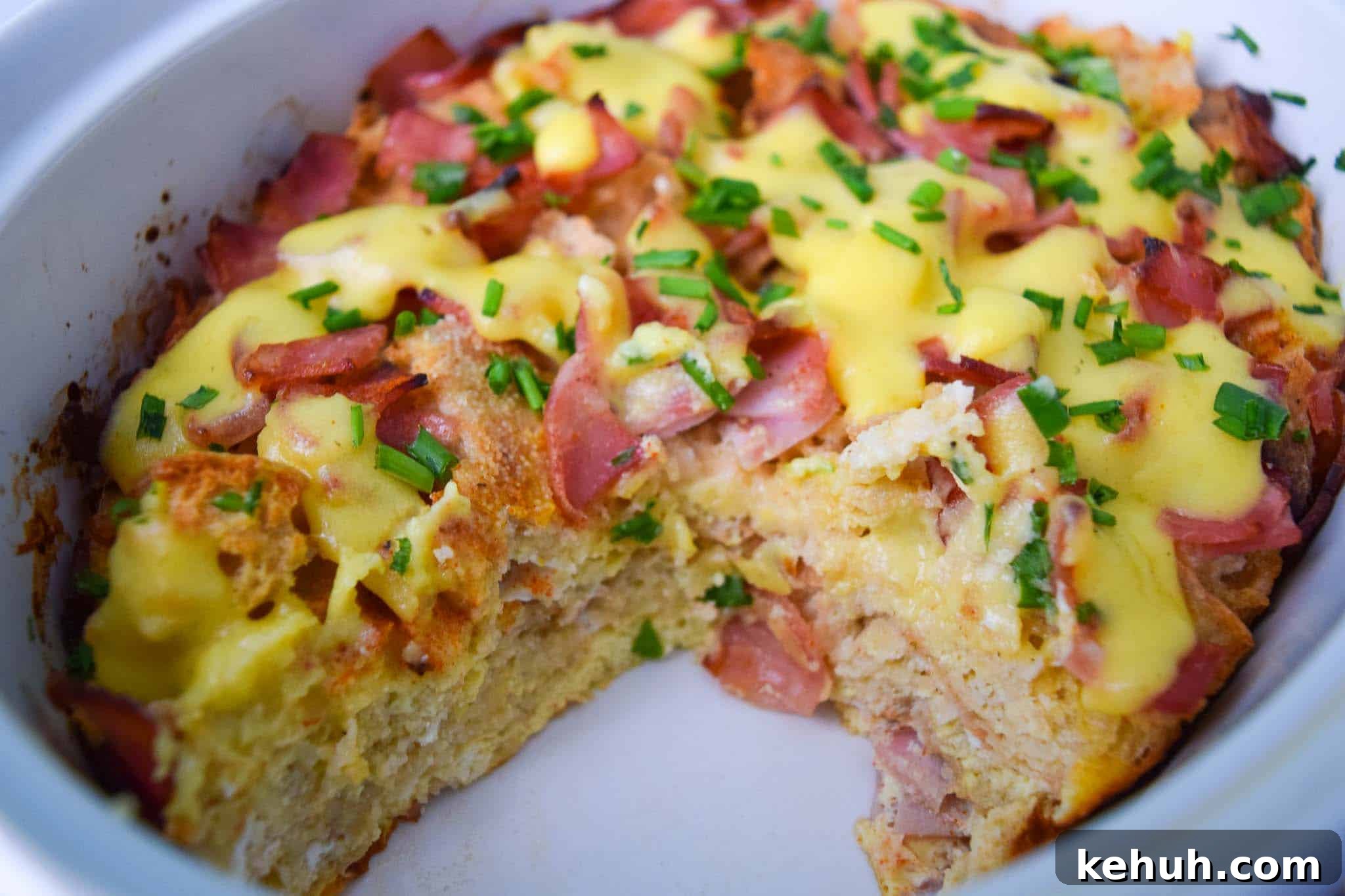 Overnight Eggs Benedict Casserole in white dish with piece missing close up