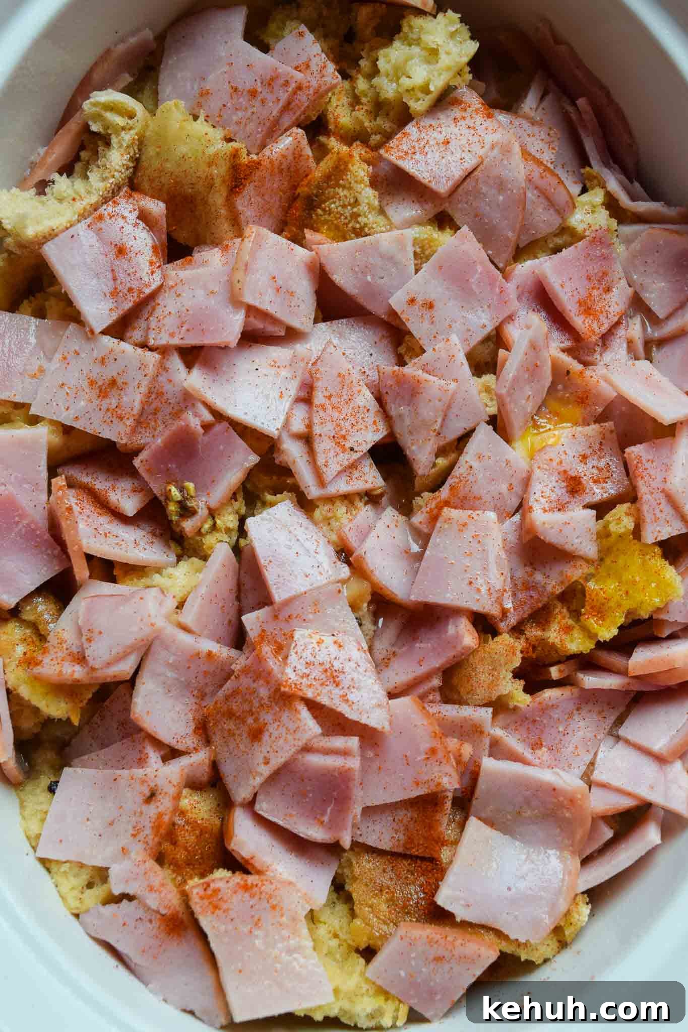 Overnight Eggs Benedict Casserole topped with bacon in white dish overhead shot