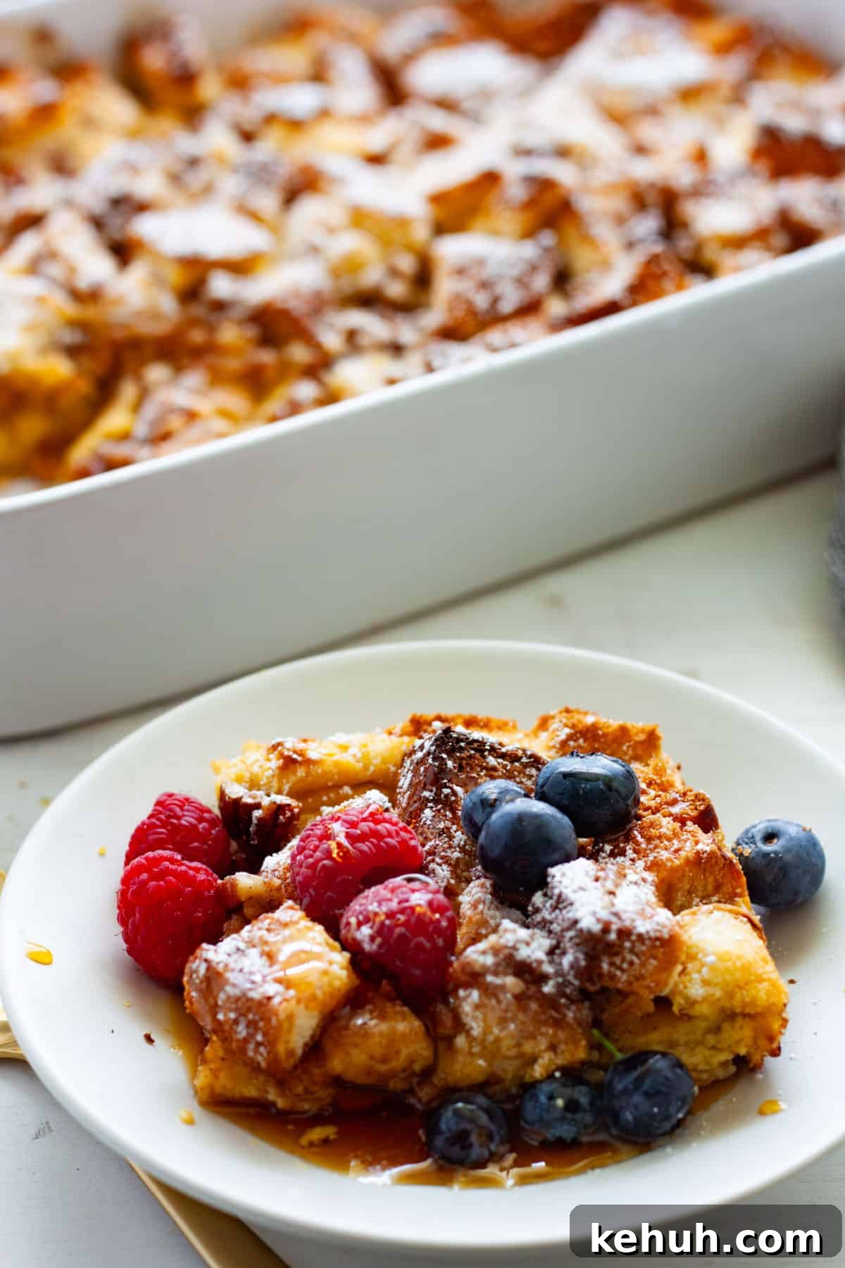 Brioche French Toast Casserole Recipe for Brunch and Holidays 2 A piece of brioche French toast casserole on a small plate with the casserole dish in the background.
