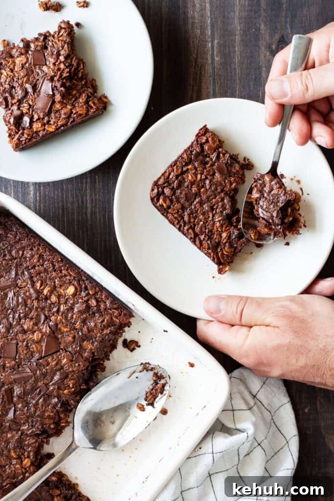 Brioche French Toast Casserole Recipe for Brunch and Holidays 13 Chocolate Baked Oatmeal in a baking dish with two portions on small plates and a hand taking a spoonful from one portion.