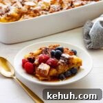 A piece of brioche French toast casserole on a small plate with the casserole dish in the background.