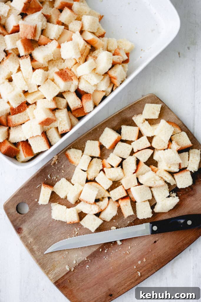 Brioche French Toast Casserole Recipe for Brunch and Holidays 5 a knife on a cutting board with brioche bread cubes and a baking dish with more bread cubes.