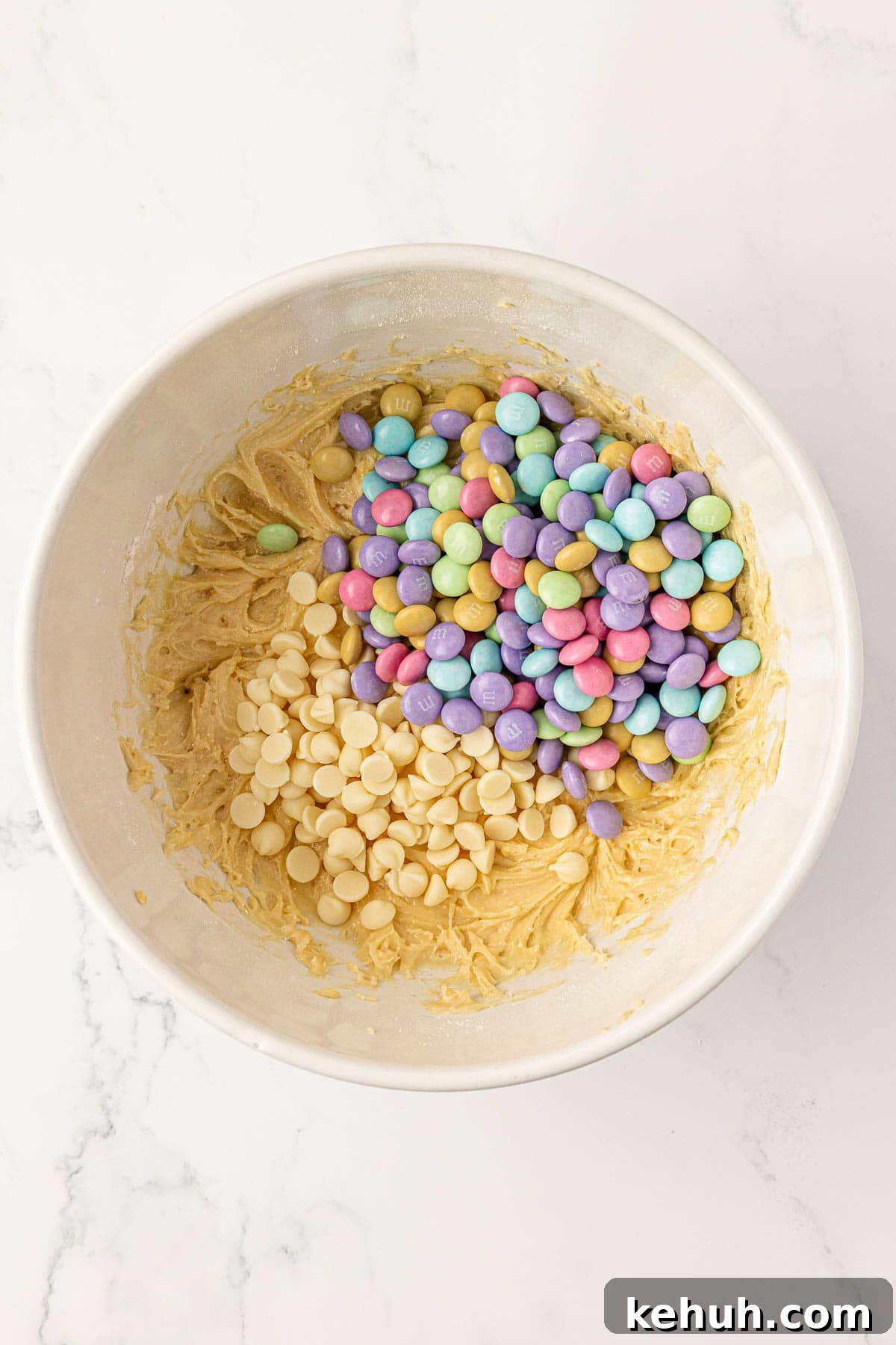 adding the white chocolate chips and m&m's to the cake mix batter