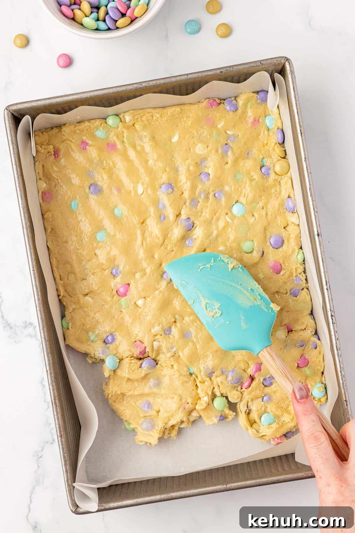 Pressing the cookie batter into the baking dish with a rubber spatula
