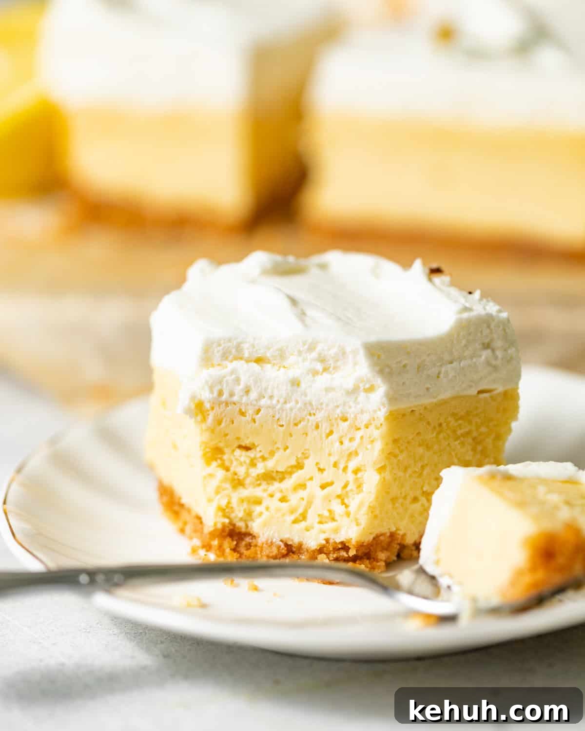 Tangy Lemon Bars with Crisp Graham Cracker Crust 3 lemon bars on a plate with a spoon.