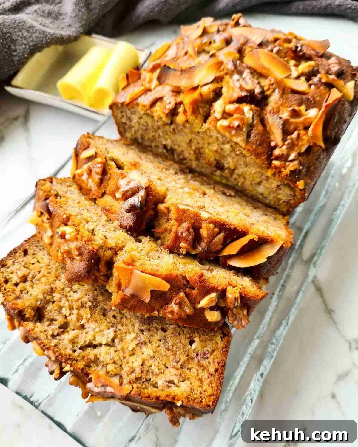 Loaf of freshly baked banana bread with half the loaf sliced into thick slices sitting on top of a wooden board