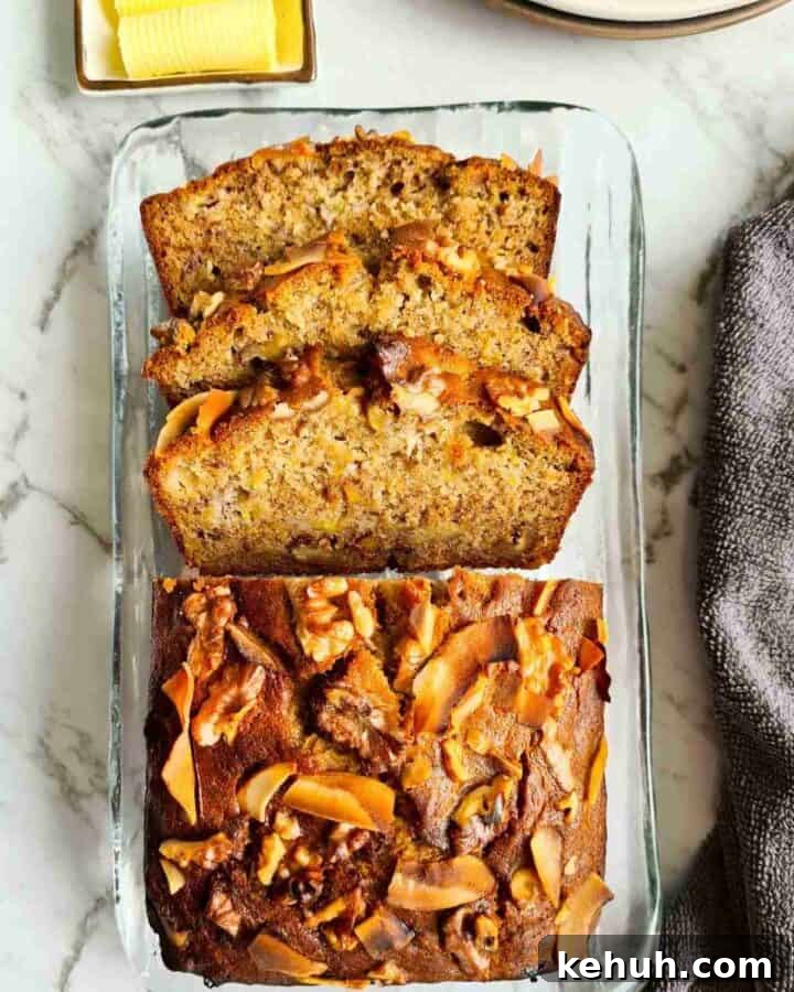 A loaf of banana bread on a glass plate with of the loaf thickly sliced
