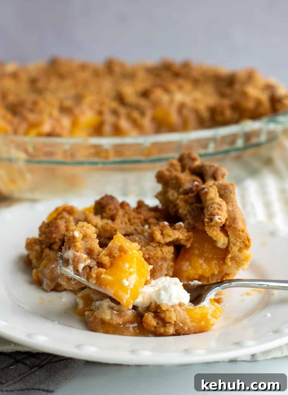Sourdough Peach Crumb Pie Recipe with Flaky Rustic Crust 2 A slice of sourdough peach pie on a plate with a buttery crumb topping.