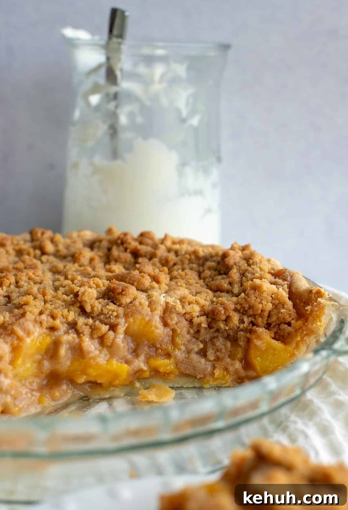 Sourdough Peach Crumb Pie Recipe with Flaky Rustic Crust 12 A peach pie missing a few slices sits next to a jar of fresh whipped cream.