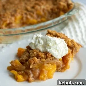 Sourdough Peach Crumb Pie Recipe with Flaky Rustic Crust 18 A slice of sourdough peach pie on a plate with whipped cream on top.