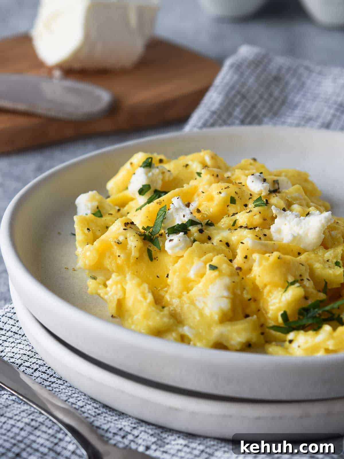 Creamy Goat Cheese Scrambled Eggs with Herbs and Cherry Tomatoes 2 Close-up of scrambled eggs with goat cheese on a white plate.