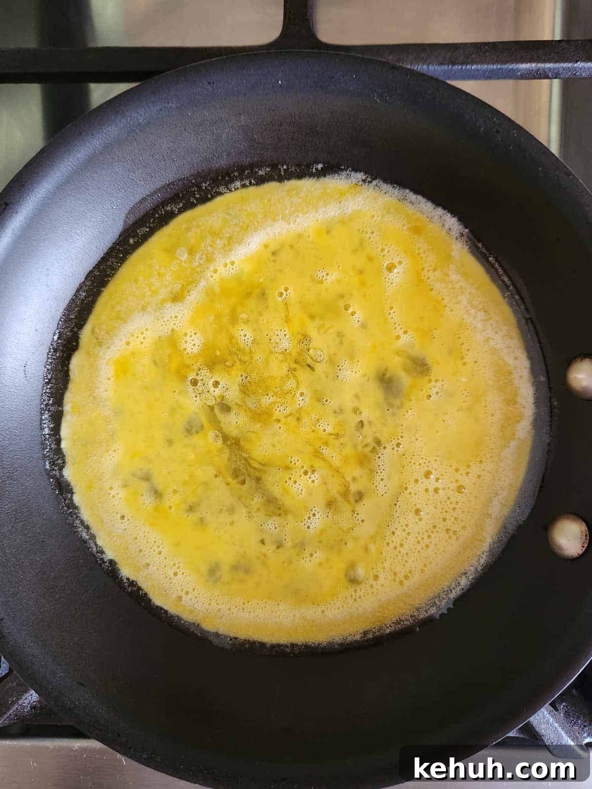 Creamy Goat Cheese Scrambled Eggs with Herbs and Cherry Tomatoes 6 Whisked eggs in a small black pan.