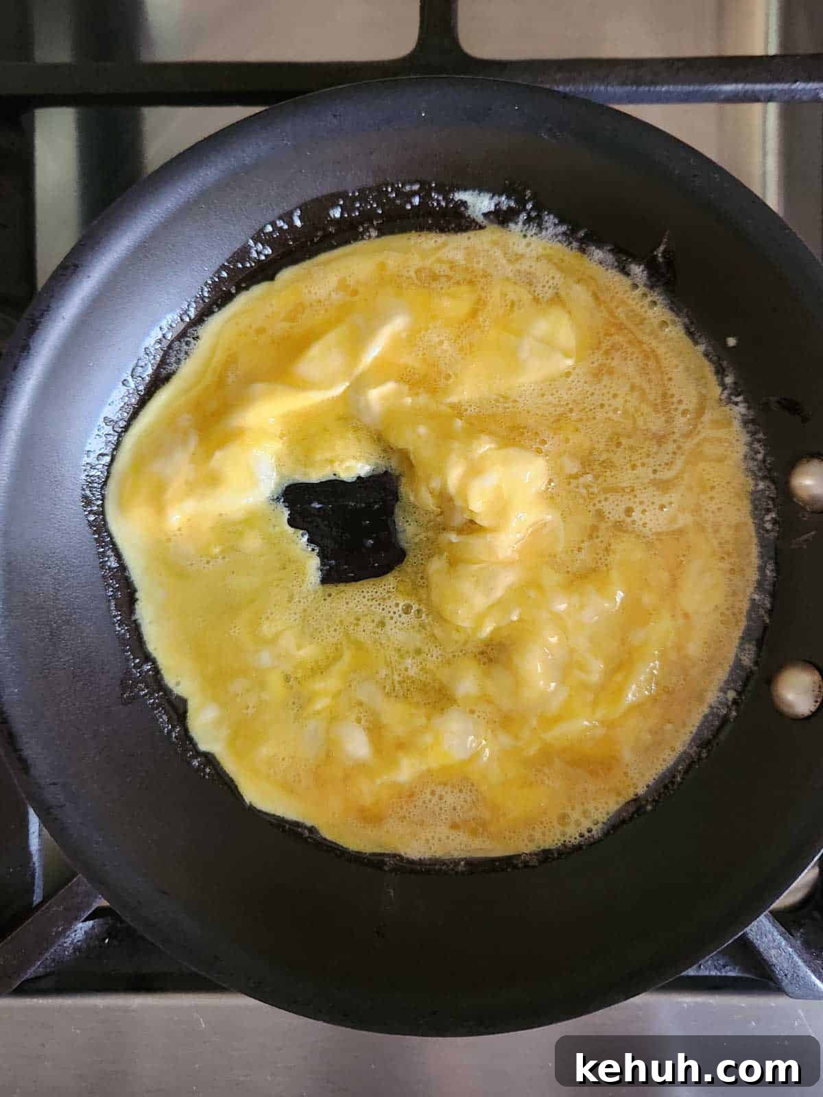 Creamy Goat Cheese Scrambled Eggs with Herbs and Cherry Tomatoes 7 Making curds for scrambled eggs in a skillet.