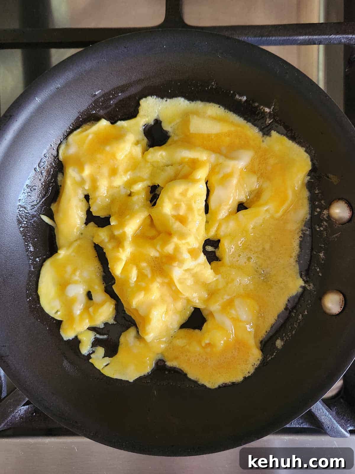Creamy Goat Cheese Scrambled Eggs with Herbs and Cherry Tomatoes 8 Semi-cooked scrambled eggs in a skillet.