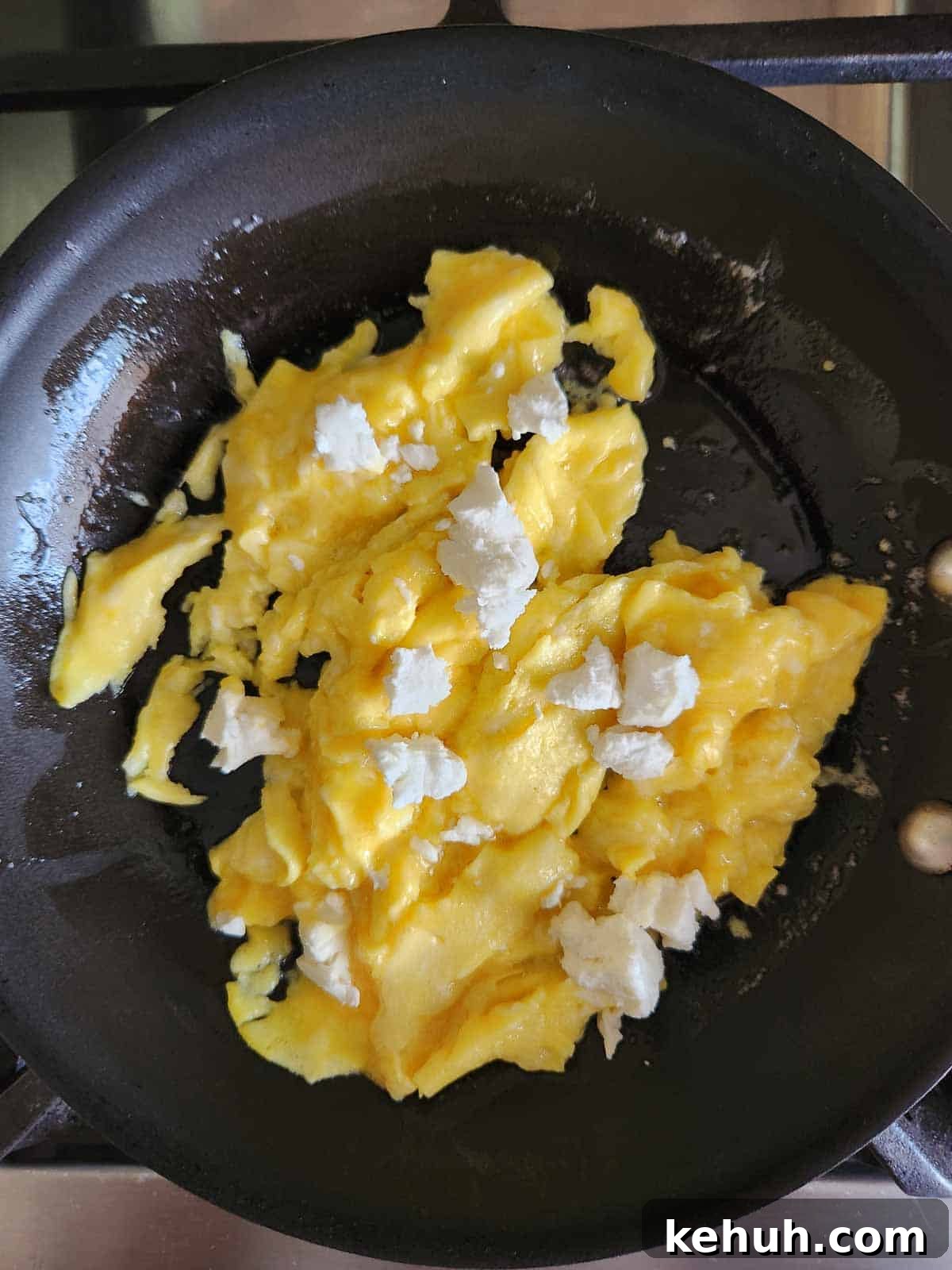 Creamy Goat Cheese Scrambled Eggs with Herbs and Cherry Tomatoes 9 Scrambled eggs with goat cheese on top in a skillet.