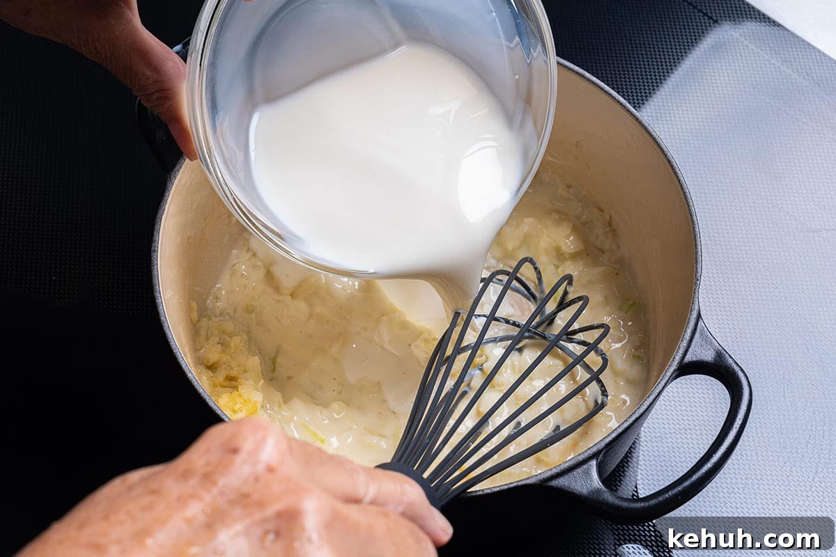 Creamy Parmesan Spinach Recipe — Quick Sautéed Side Dish 5 pot with flour, garlic and onion having milk poured in