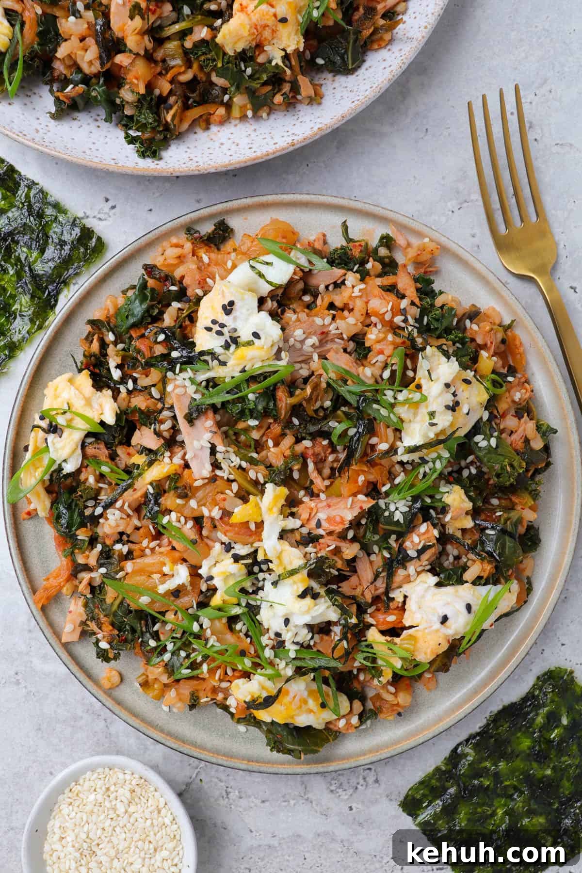 Spicy Tuna and Kimchi Fried Rice Recipe for Quick Weeknight Meals 6 Fried rice on plate with fork, seaweed and sesame seeds on the side.