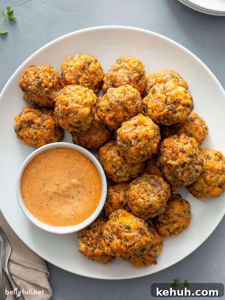 Overhead sausage balls on a plate with a bowl of remoulade sauce