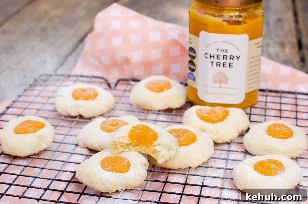 Thumbprint Cookies with Jam, Curd, or Chocolate Filling 18 Passion fruit thumbprint cookies on a black cooling rack with a jar of The Cherry Tree passion fruit curd on the side