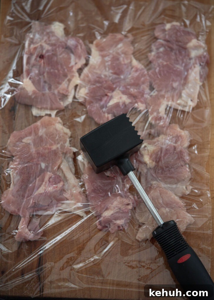 Pounding chicken thighs with a meat mallet to flatten
