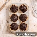 Six double chocolate banana muffins with mini chocolate chips in a muffin tin.