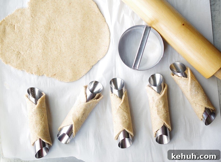 cannoli tubes wrapped with cannoli dough before frying in oil