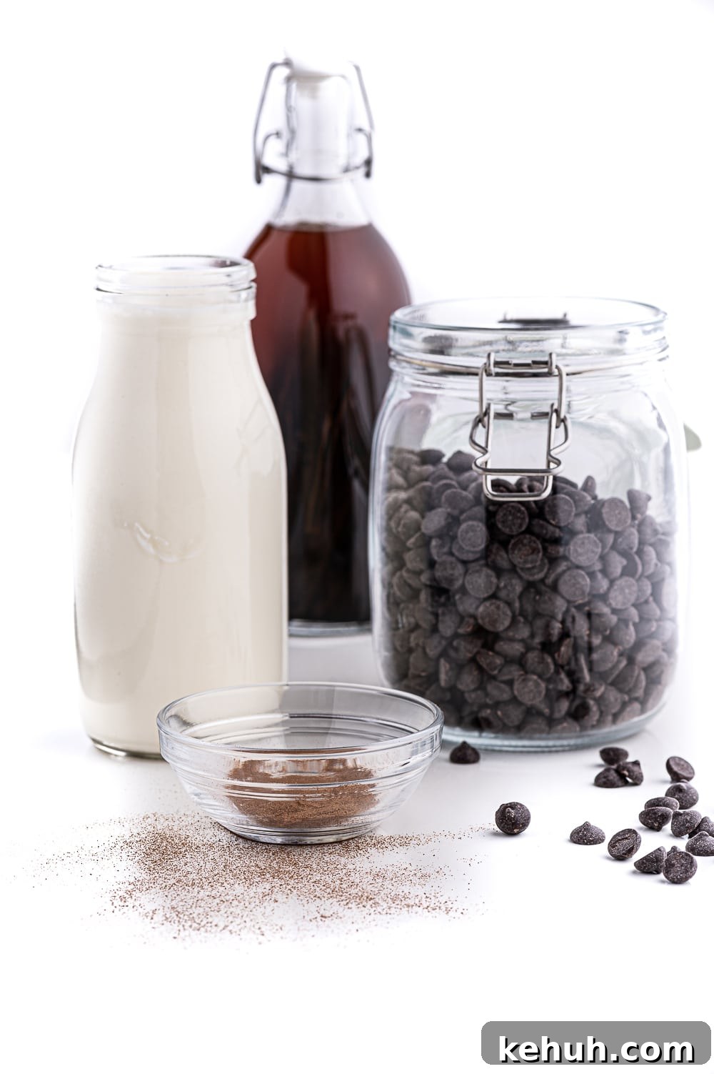 Keto Chocolate Mousse Recipe Without Eggs — Silky & Low-Carb 3 Jars filled with fresh whipping cream, chocolate chips, expresso powder and vanilla sitting on a bright white table against a bright white background.