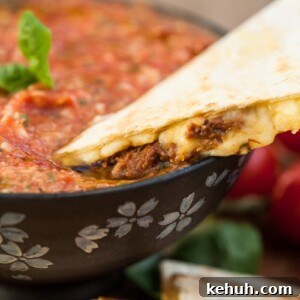 Italian Beef & Roasted Red Pepper Quesadilla Recipe 7 quesadilla being dipped in salsa
