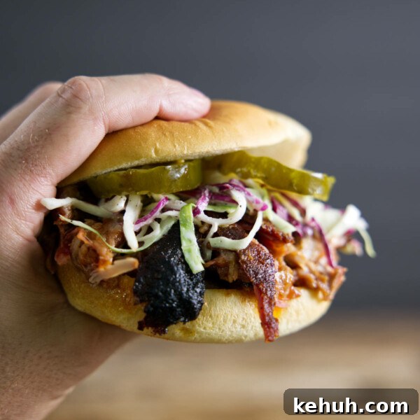 Pulled pork sandwich made from smoked pork butt (smoked pork shoulder). With pickles, slaw, and BBQ sauce.