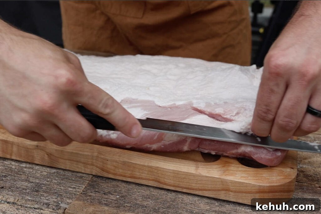 Trimming excess fat from the pork belly.